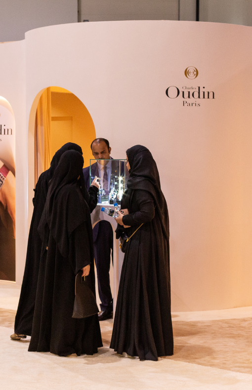 A group of women dressed in traditional clothing looking at a watch in a glass case