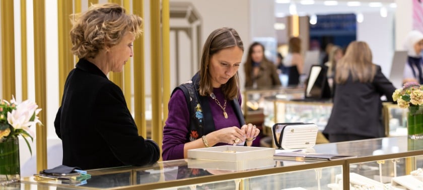 A group of individuals examines jewellery in a store. Image 