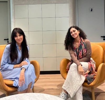 Two women seated on chairs in a well-lit room, engaged in conversation.
