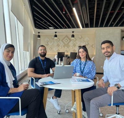 A group of four people gathered around a table collaborating on a project.