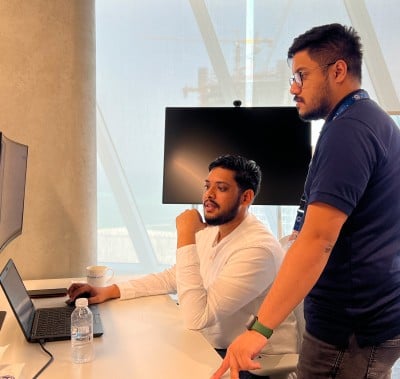 Two men examine a computer screen, demonstrating teamwork and concentration on the task at hand.